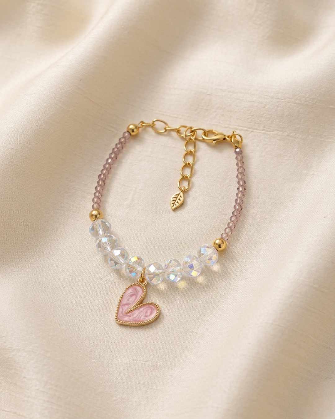 Delicate bracelet with iridescent clear crystal beads, small lilac seed beads, pink enamel marble heart charm and gold leaf extender clasp