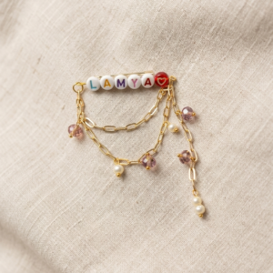 Personalised name brooch pin with multicolour letter beads, draped gold paperclip chains and dangling crystal and pearl charms