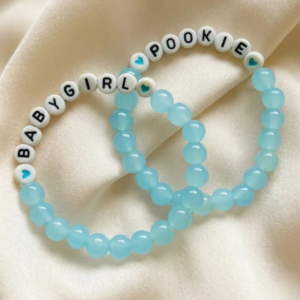 Two stretchy light blue jade bead bracelets with white letter beads spelling BABYGIRL and POOKIE with blue heart accent beads