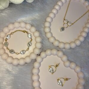 Matching coin pearl jewelry set including bracelet, gold chain necklace with pearl pendant, and dangle earrings on heart-shaped pearl trays