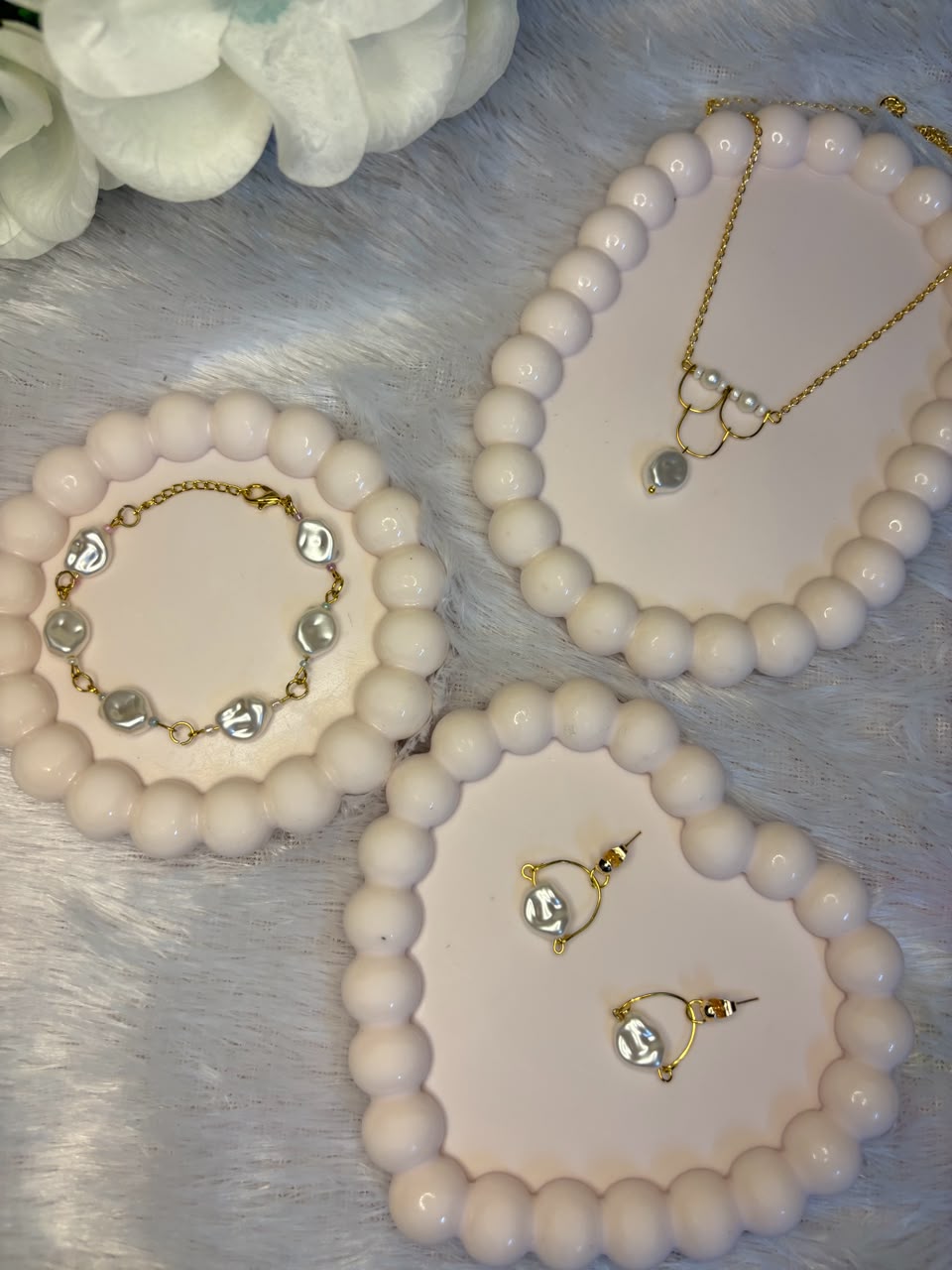 Matching coin pearl jewelry set including bracelet, gold chain necklace with pearl pendant, and dangle earrings on heart-shaped pearl trays