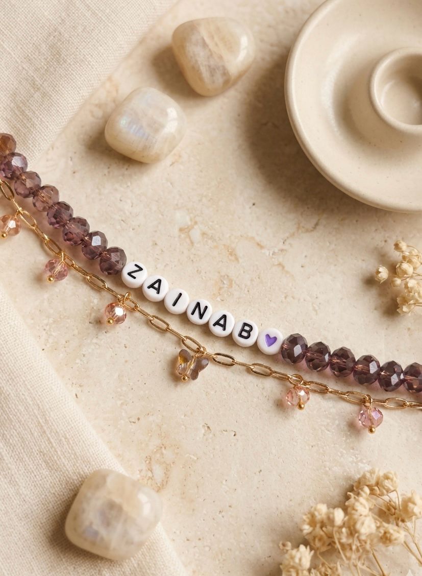 Personalised name bracelet with brown crystal beads, white letter beads spelling a name, and a gold paperclip chain with dangling crystal charms