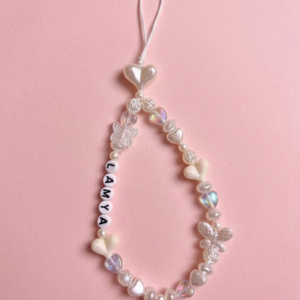 Personalised all-white and ivory beaded phone charm with pearl heart beads, iridescent crystal beads, rose beads, butterfly charms and custom name letter beads on a white cord loop