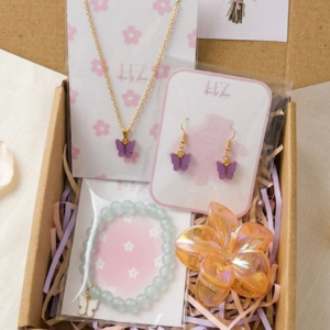 Gift hamper box with purple butterfly necklace, matching earrings, mint bead bracelet with butterfly charm, floral hair clip and tulip greeting card in kraft box with pastel fillers